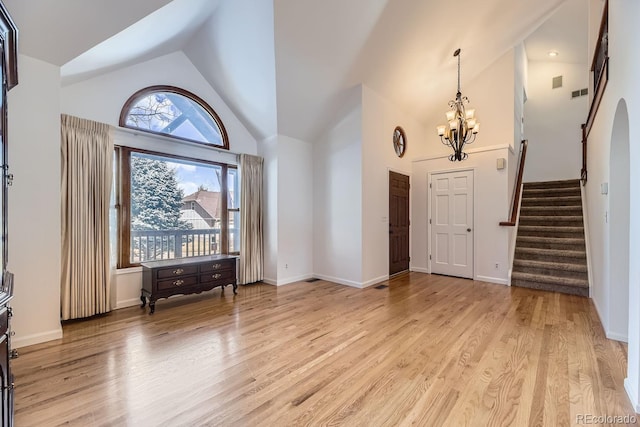 foyer entrance featuring an inviting chandelier, high vaulted ceiling, stairs, and light wood-style floors