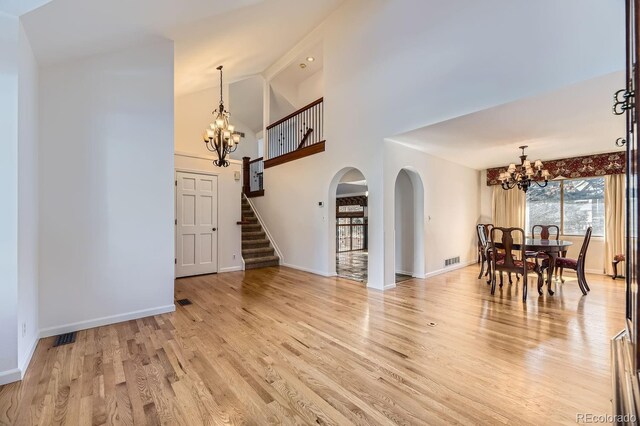 dining space with visible vents, high vaulted ceiling, light wood-style flooring, stairway, and a chandelier