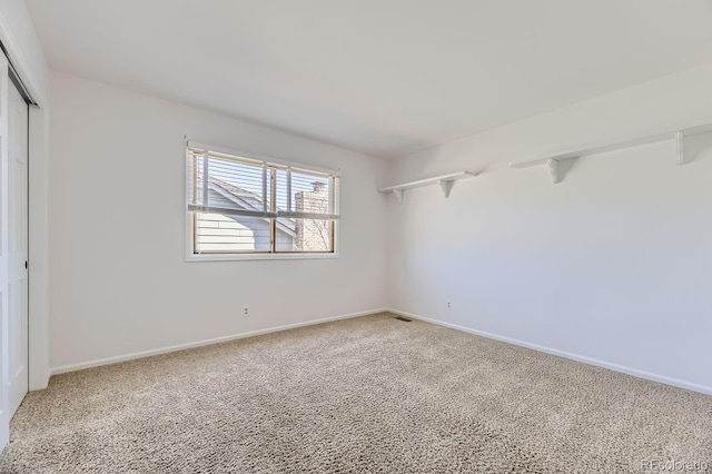 carpeted empty room with visible vents and baseboards