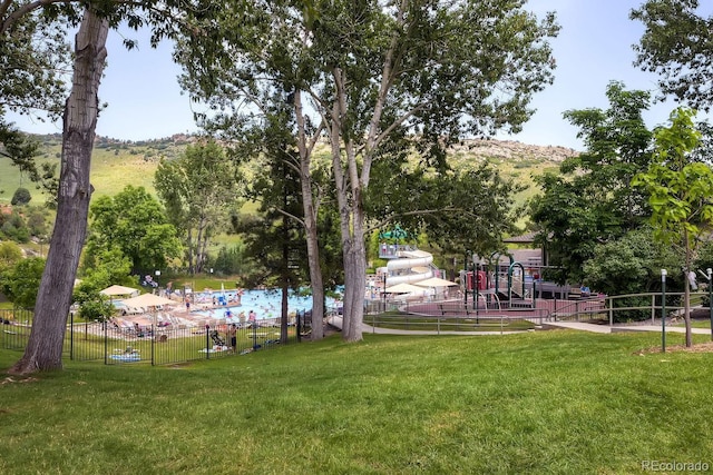 surrounding community featuring playground community, a lawn, and fence