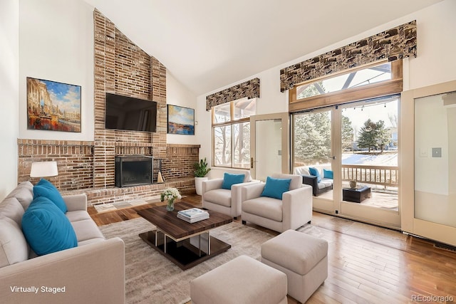 living area with hardwood / wood-style flooring, a fireplace, and high vaulted ceiling