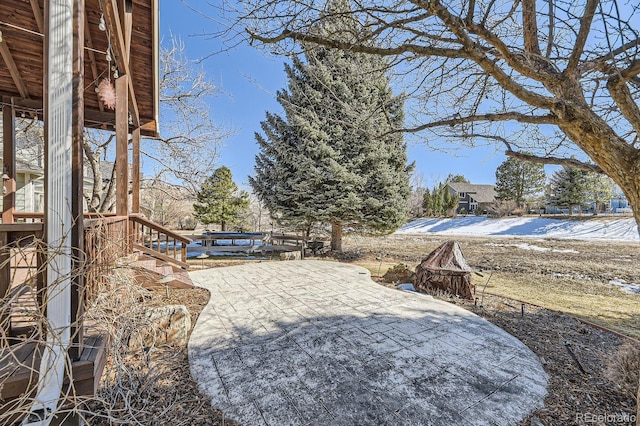 yard layered in snow with a patio area