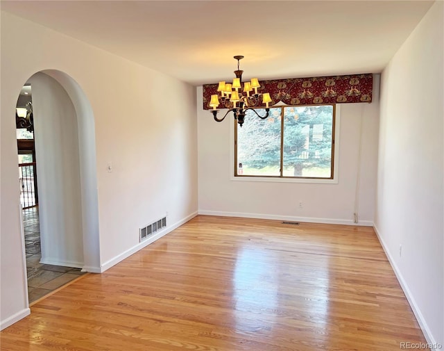 27 Buckthorn Dr, Littleton, CO 80127 - spare room with a notable chandelier, baseboards, visible vents, arched walkways, and light wood finished floors