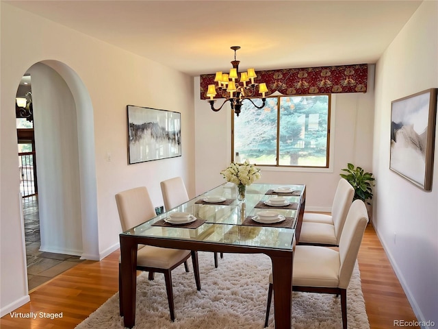 27 Buckthorn Dr, Littleton, CO 80127 - dining room featuring baseboards, arched walkways, light wood-type flooring, and an inviting chandelier