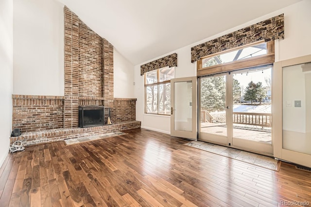 27 Buckthorn Dr, Littleton, CO 80127 - unfurnished living room featuring hardwood / wood-style floors, high vaulted ceiling, baseboards, and a brick fireplace