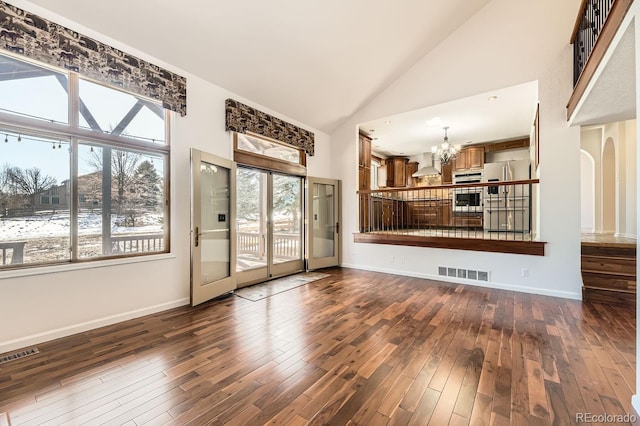 27 Buckthorn Dr, Littleton, CO 80127 - unfurnished living room with dark wood-style flooring, visible vents, high vaulted ceiling, and a chandelier
