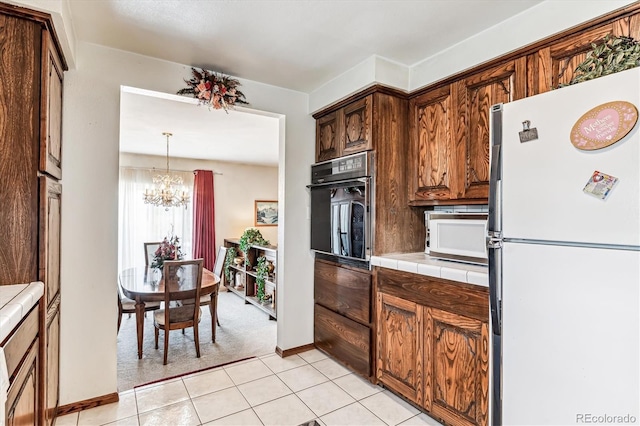 kitchen with tile counters, a notable chandelier, pendant lighting, white appliances, and light tile patterned floors