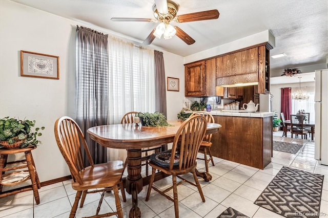 tiled dining area with a textured ceiling and ceiling fan with notable chandelier