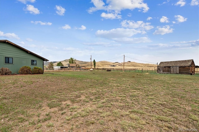 view of yard featuring a mountain view, a rural view, and an outbuilding