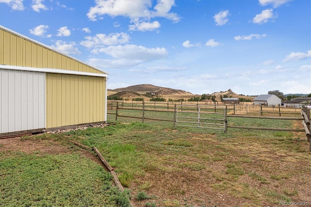 view of yard featuring a mountain view, a rural view, and an outdoor structure