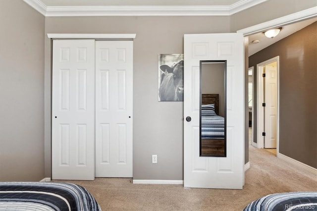carpeted bedroom featuring a closet, crown molding, and baseboards