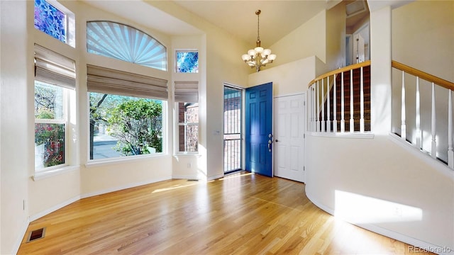 entryway with visible vents, wood finished floors, a notable chandelier, and high vaulted ceiling