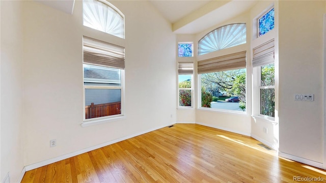 unfurnished room with baseboards, visible vents, and wood finished floors