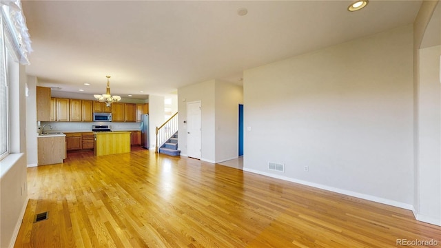 unfurnished living room with an inviting chandelier, recessed lighting, light wood finished floors, and visible vents