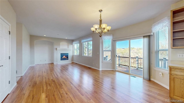 unfurnished living room featuring baseboards, a chandelier, visible vents, and light wood-style floors