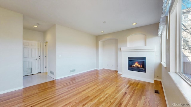 unfurnished living room featuring visible vents, recessed lighting, wood finished floors, and a tile fireplace