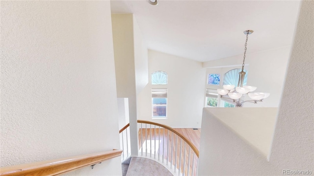 staircase with a textured wall and a chandelier