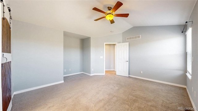empty room featuring visible vents, a ceiling fan, carpet floors, and lofted ceiling