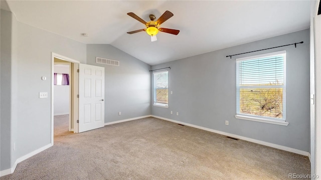 carpeted empty room featuring baseboards, ceiling fan, lofted ceiling, and visible vents