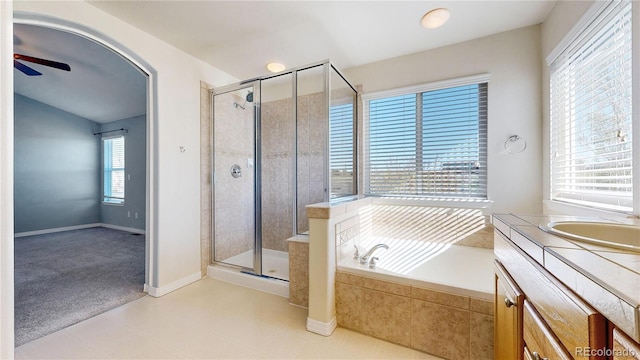 bathroom featuring a ceiling fan, a garden tub, a stall shower, vanity, and baseboards
