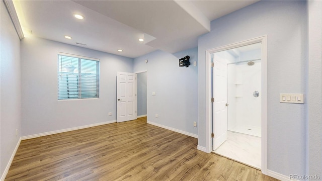 unfurnished bedroom featuring visible vents, baseboards, recessed lighting, light wood-style flooring, and ensuite bath