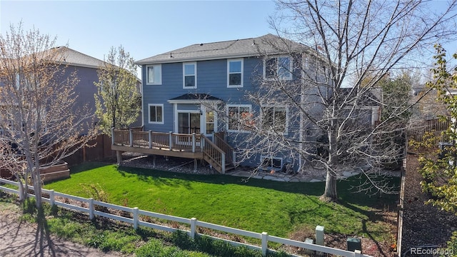 back of house with a fenced backyard, a wooden deck, and a lawn