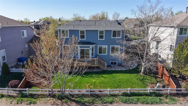 rear view of house with a lawn, a wooden deck, and a fenced backyard