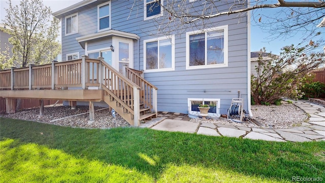 back of property featuring a lawn, a deck, and fence
