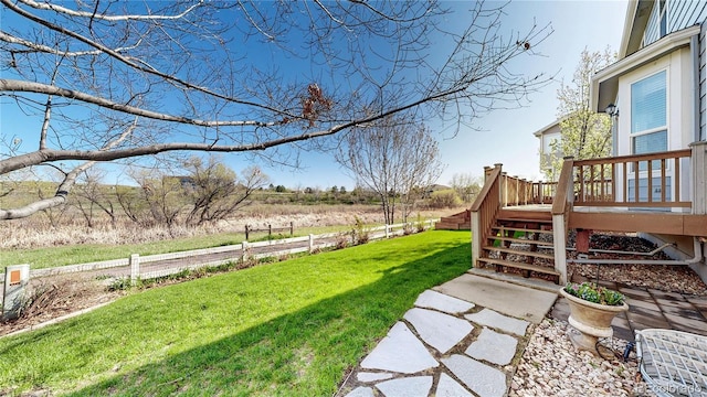view of yard with fence, a wooden deck, and stairs