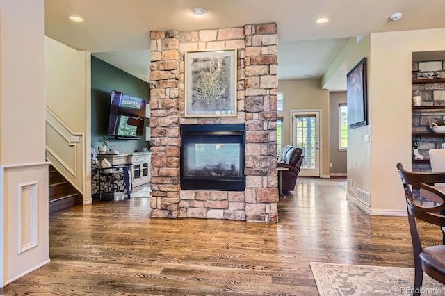 living area featuring a fireplace, wood finished floors, stairway, and baseboards