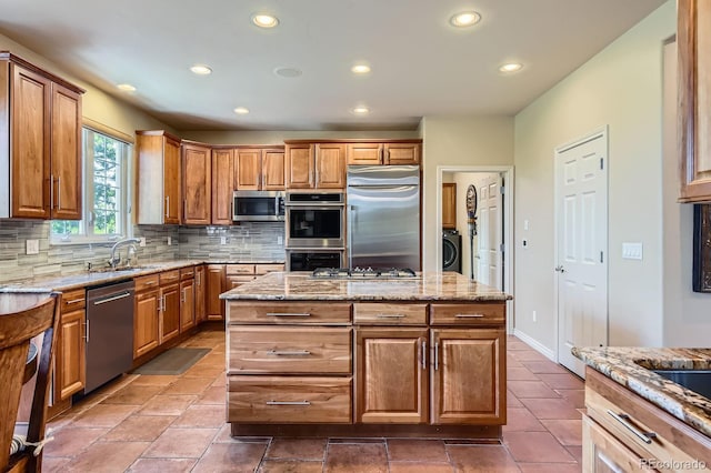 kitchen featuring appliances with stainless steel finishes, a sink, recessed lighting, backsplash, and washer / clothes dryer