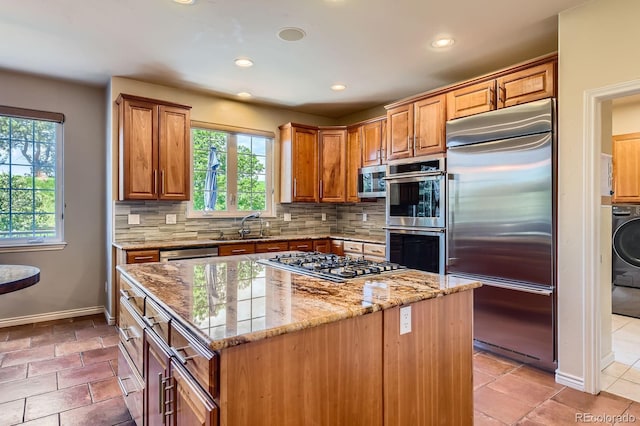 kitchen featuring stainless steel appliances, healthy amount of natural light, a sink, light stone counters, and recessed lighting