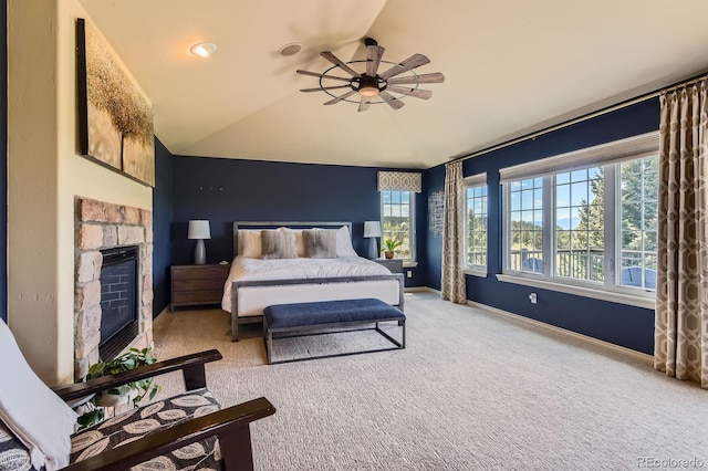 carpeted bedroom with lofted ceiling, multiple windows, a stone fireplace, and baseboards