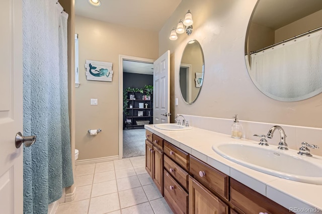 bathroom featuring tile patterned floors, double vanity, toilet, and baseboards