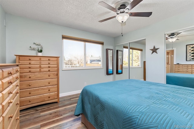 bedroom featuring a ceiling fan, a textured ceiling, baseboards, and wood finished floors