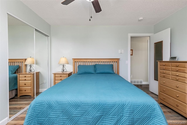 bedroom with a textured ceiling, a closet, wood finished floors, and visible vents