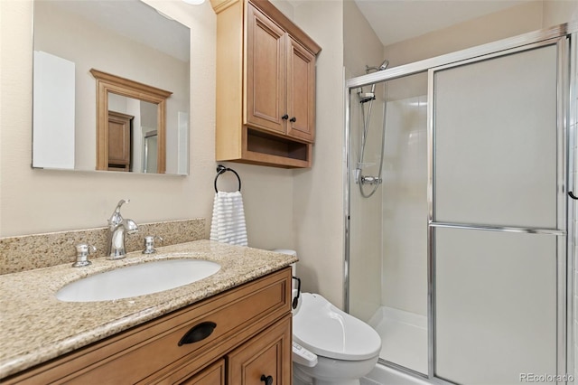 full bathroom featuring vanity, a shower stall, and toilet