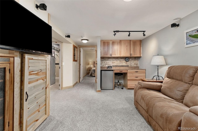 living area featuring light carpet, rail lighting, and baseboards