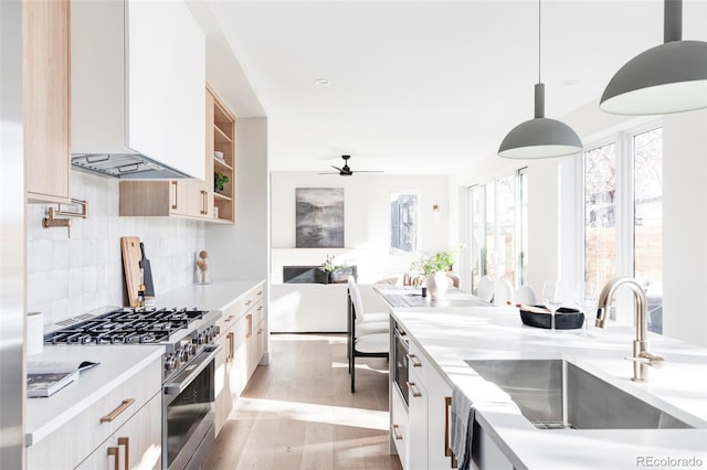 kitchen with pendant lighting, white cabinets, sink, stainless steel stove, and decorative backsplash