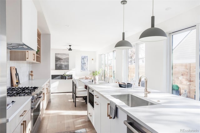 kitchen with decorative backsplash, pendant lighting, white cabinetry, and high end stainless steel range