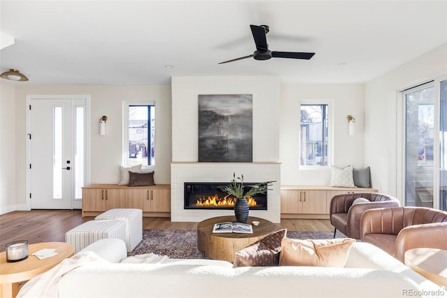 living room with ceiling fan, dark wood-type flooring, and a tiled fireplace