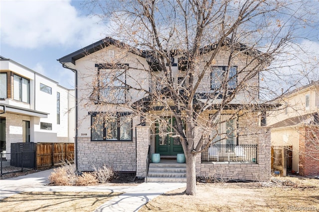 view of front of house featuring stone siding, french doors, and fence