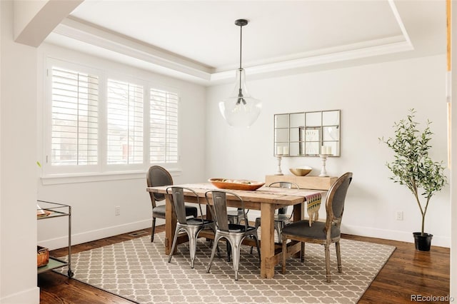 dining space with a tray ceiling, baseboards, and wood finished floors