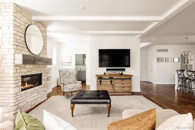 living room with visible vents, beam ceiling, wood finished floors, a large fireplace, and baseboards