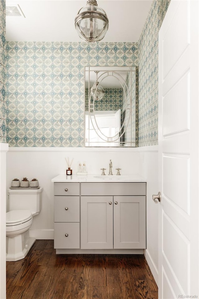 bathroom with visible vents, toilet, vanity, and wood finished floors