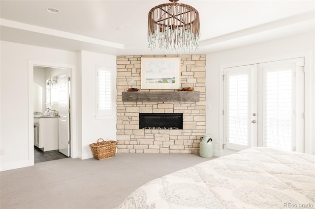 carpeted bedroom with a stone fireplace, connected bathroom, french doors, and a sink