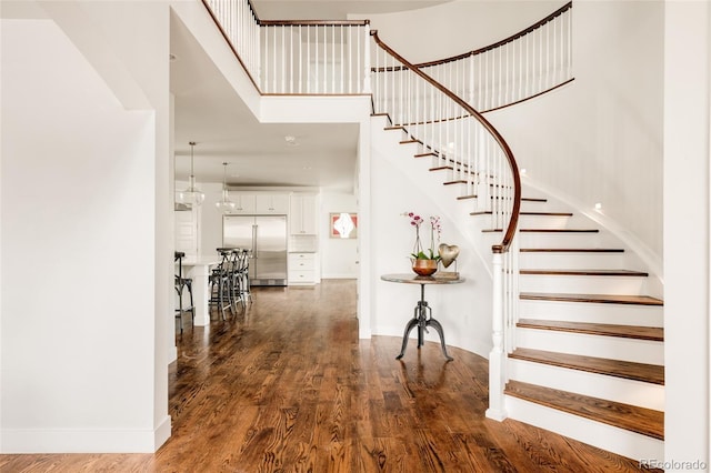 foyer with baseboards, dark wood-type flooring, a high ceiling, and stairs