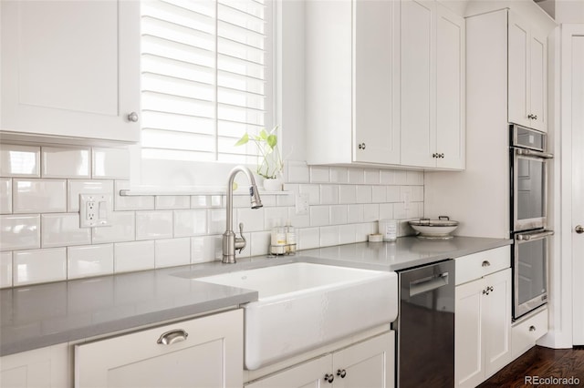 kitchen featuring a sink, stainless steel appliances, tasteful backsplash, and white cabinets