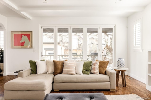 living area featuring beamed ceiling, wood finished floors, and arched walkways