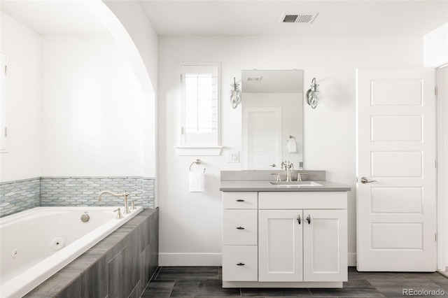 bathroom featuring visible vents, a jetted tub, wood finished floors, and vanity